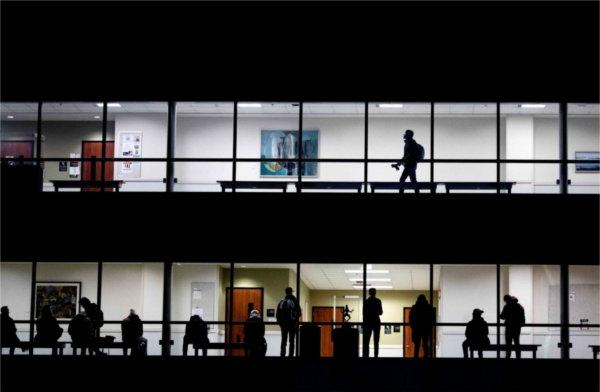  Silhouetted students are seen on two floors of an academic building as they wait for class to begin. 