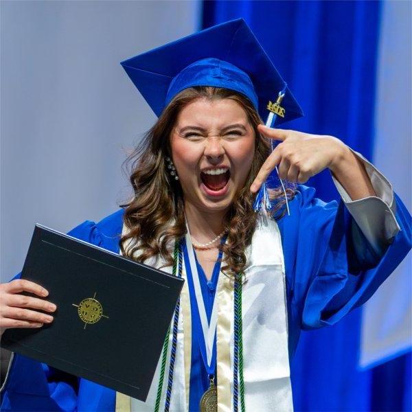 A graduate points to her diploma during a commencement ceremony.